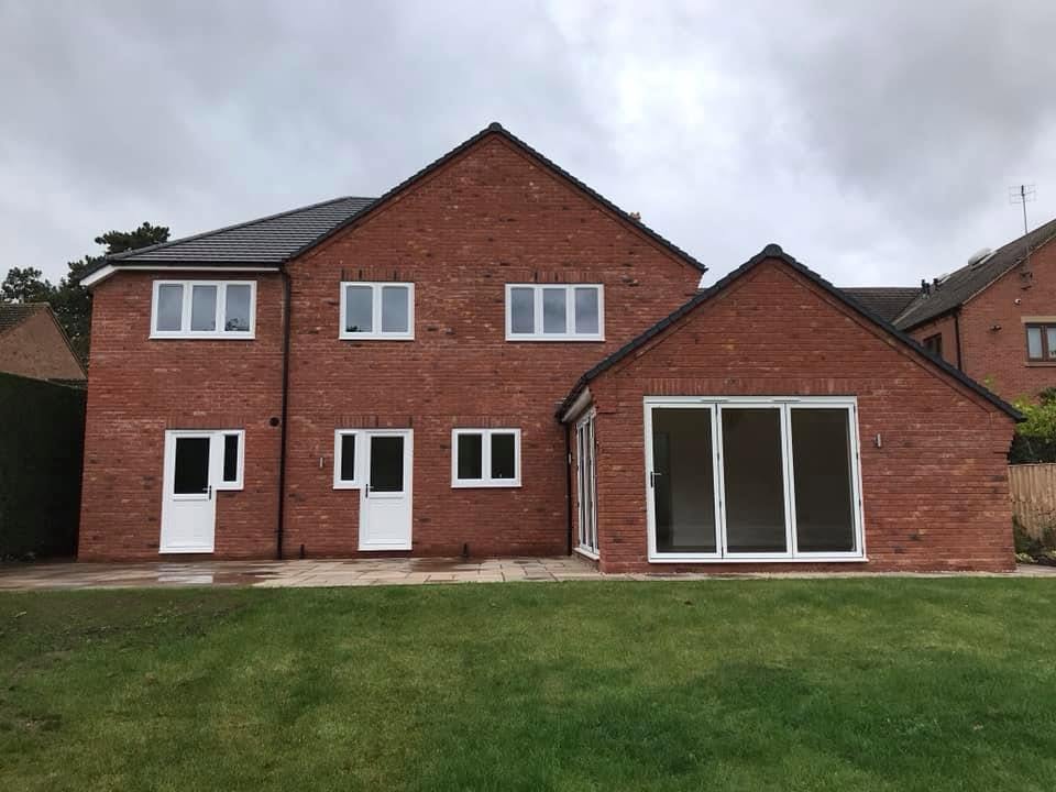 Finished four-bedroom red brick detached new-build house on High Street, Inkberrow, Worcestershire, with grey plain tile roof, aluminium bifold doors and landscaped rear garden, built by JRC Developers (J. Coote & Son Ltd)