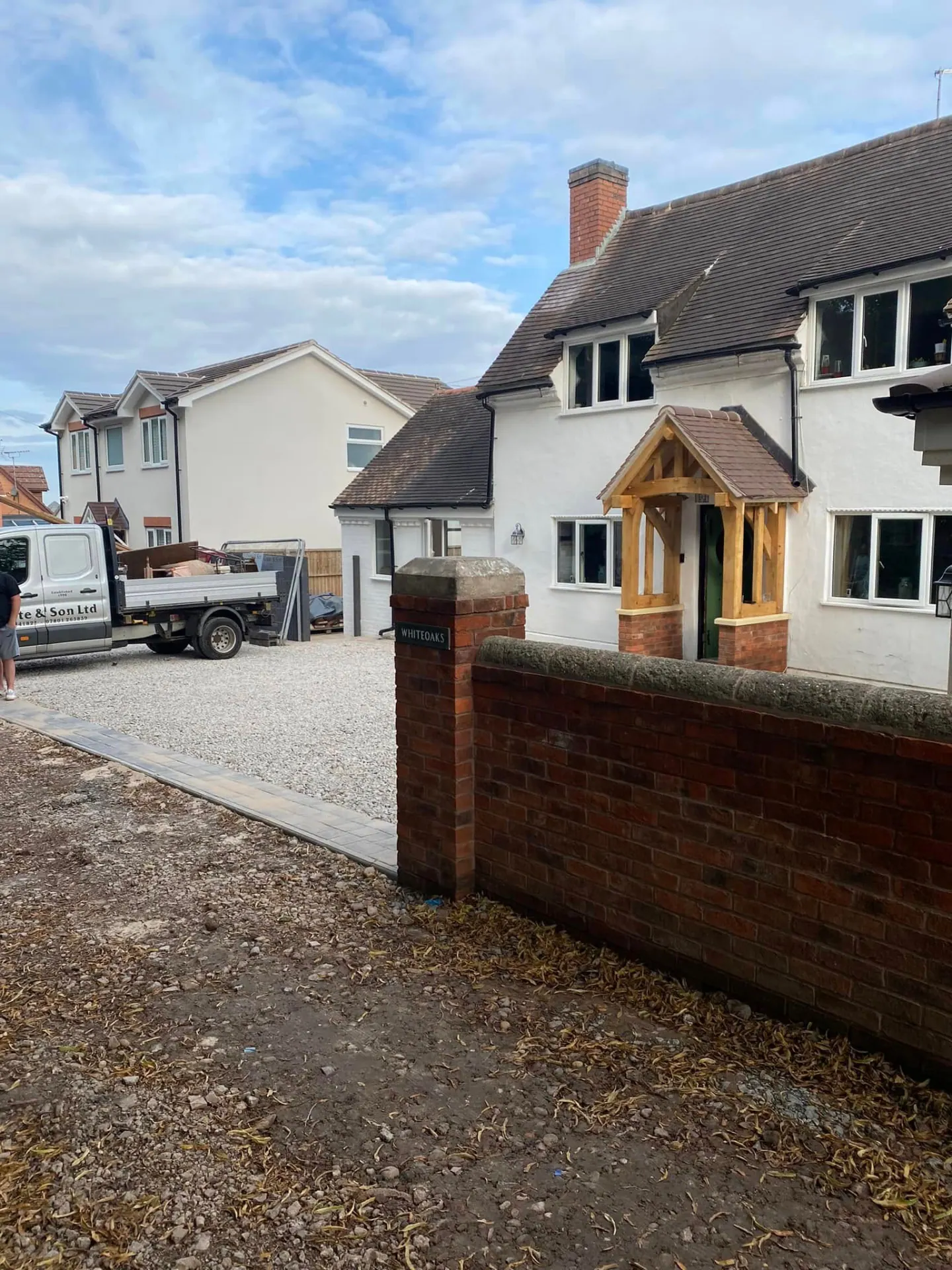 Whiteoaks in Worcestershire after completion, white rendered cottage with a hand-cut oak porch, new gravel driveway and reclaimed brick boundary wall built by JRC Developers